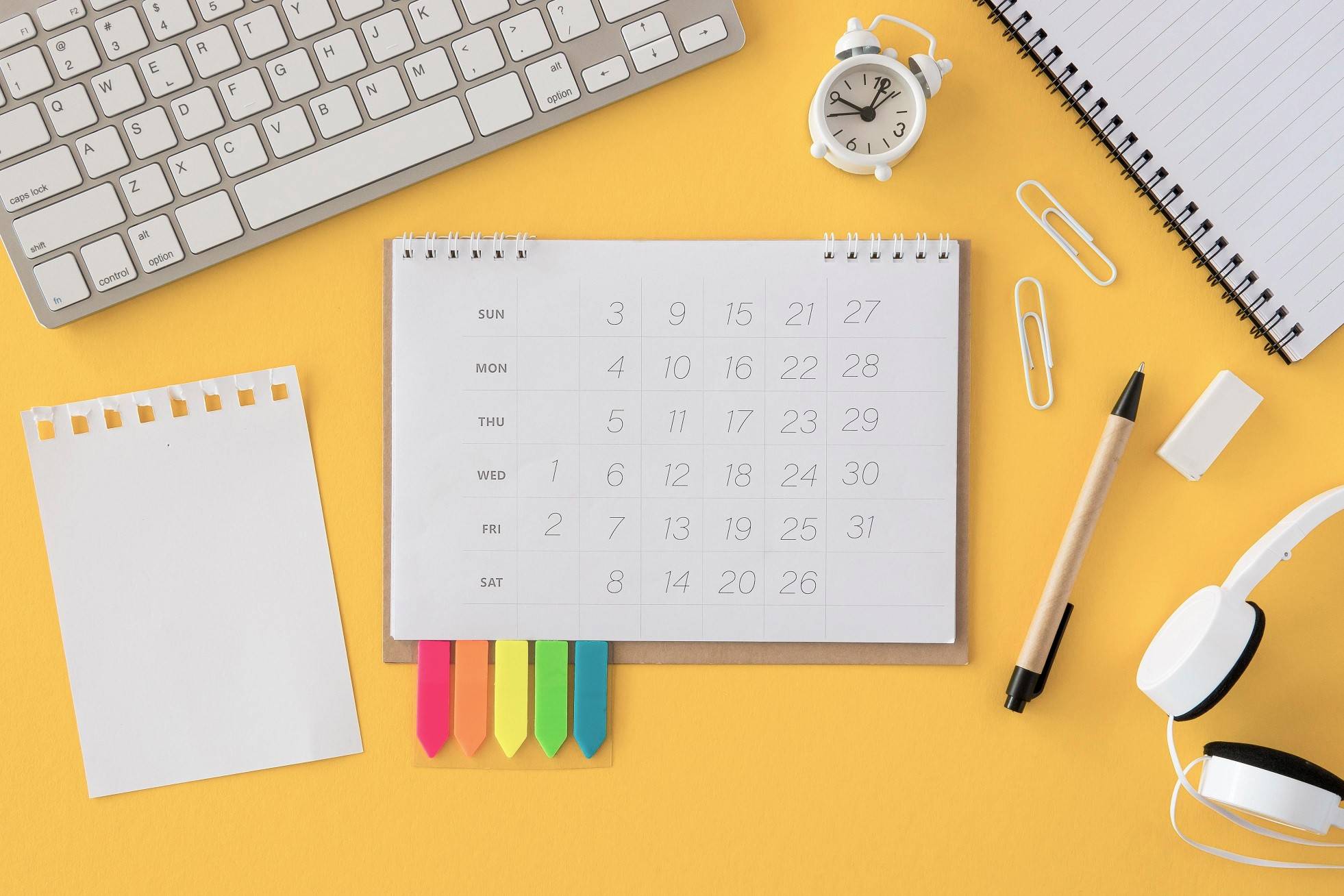 Social media calendar and office supplies on an yellow-orange desk